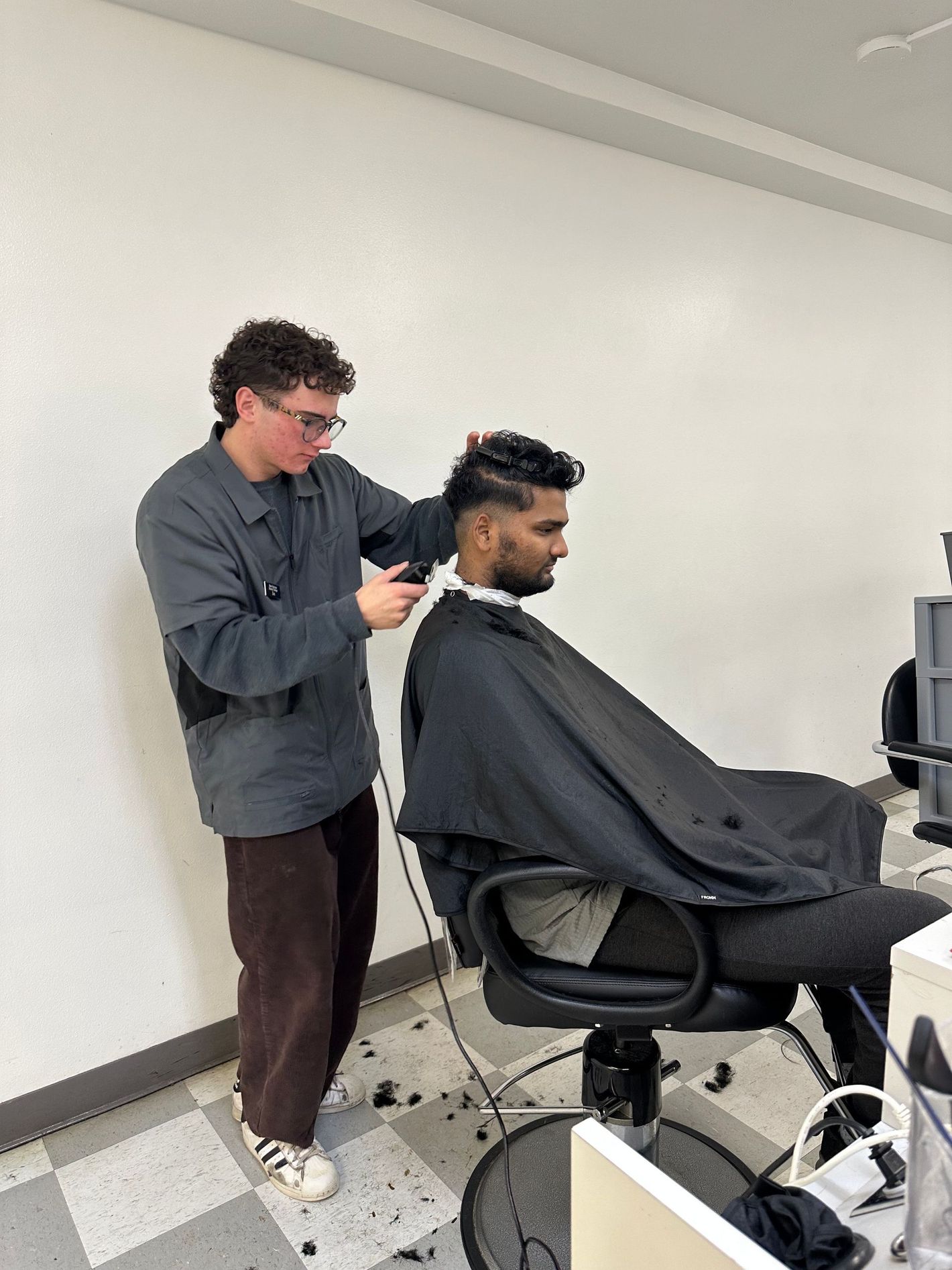 A man is getting his hair cut by a barber while sitting in a chair.