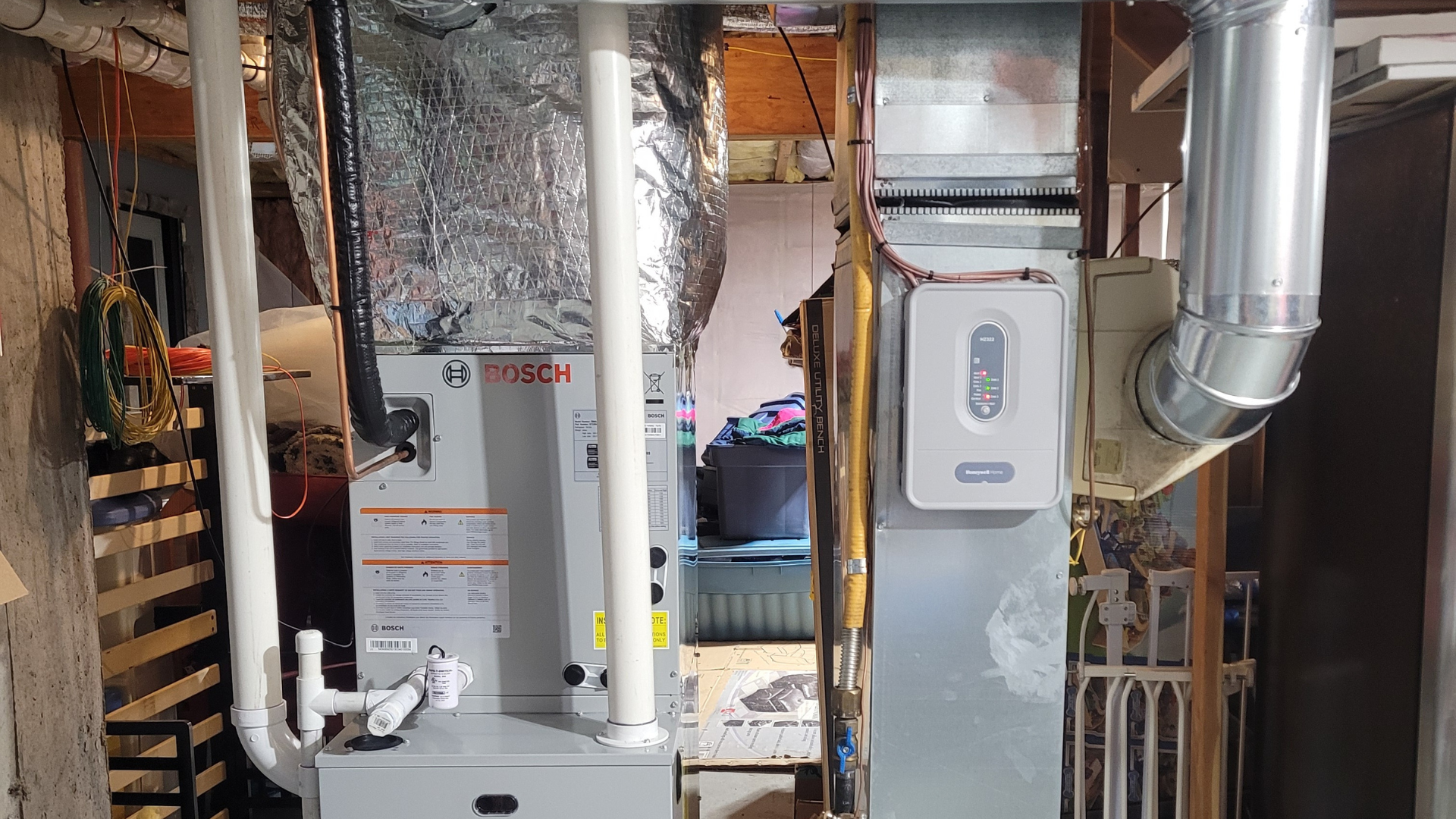 Furnace and related ductwork in a basement, featuring white and silver components.