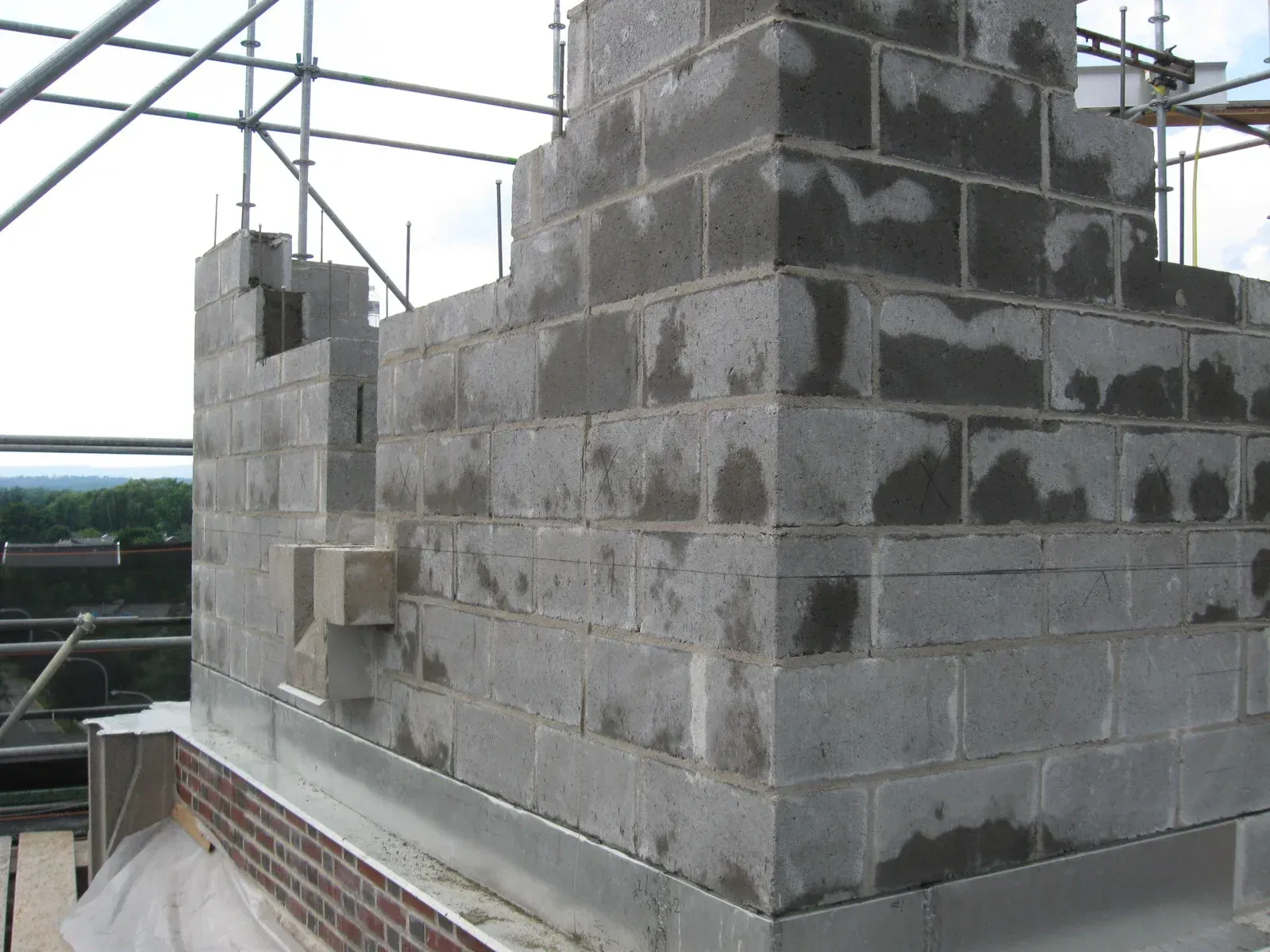 A brick wall is being built on top of a brick building