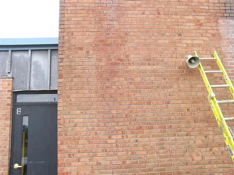 A yellow ladder is leaning against a brick wall next to a door.