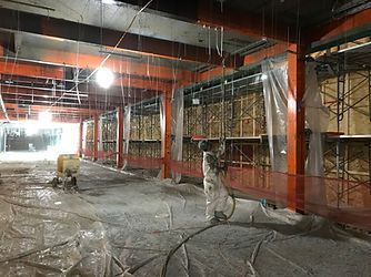 A man is spraying foam on the floor of a building under construction.