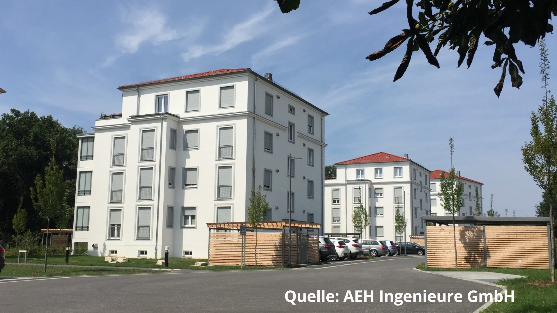 Ein großes weißes Gebäude mit einem roten Dach und einem Schild mit der Aufschrift „Quelle AEH Ingenieure GmbH“