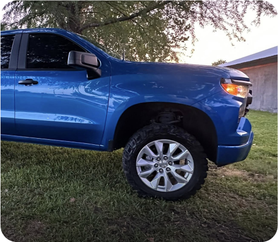 Blue pickup truck parked on grass. | Alex's Paint Body