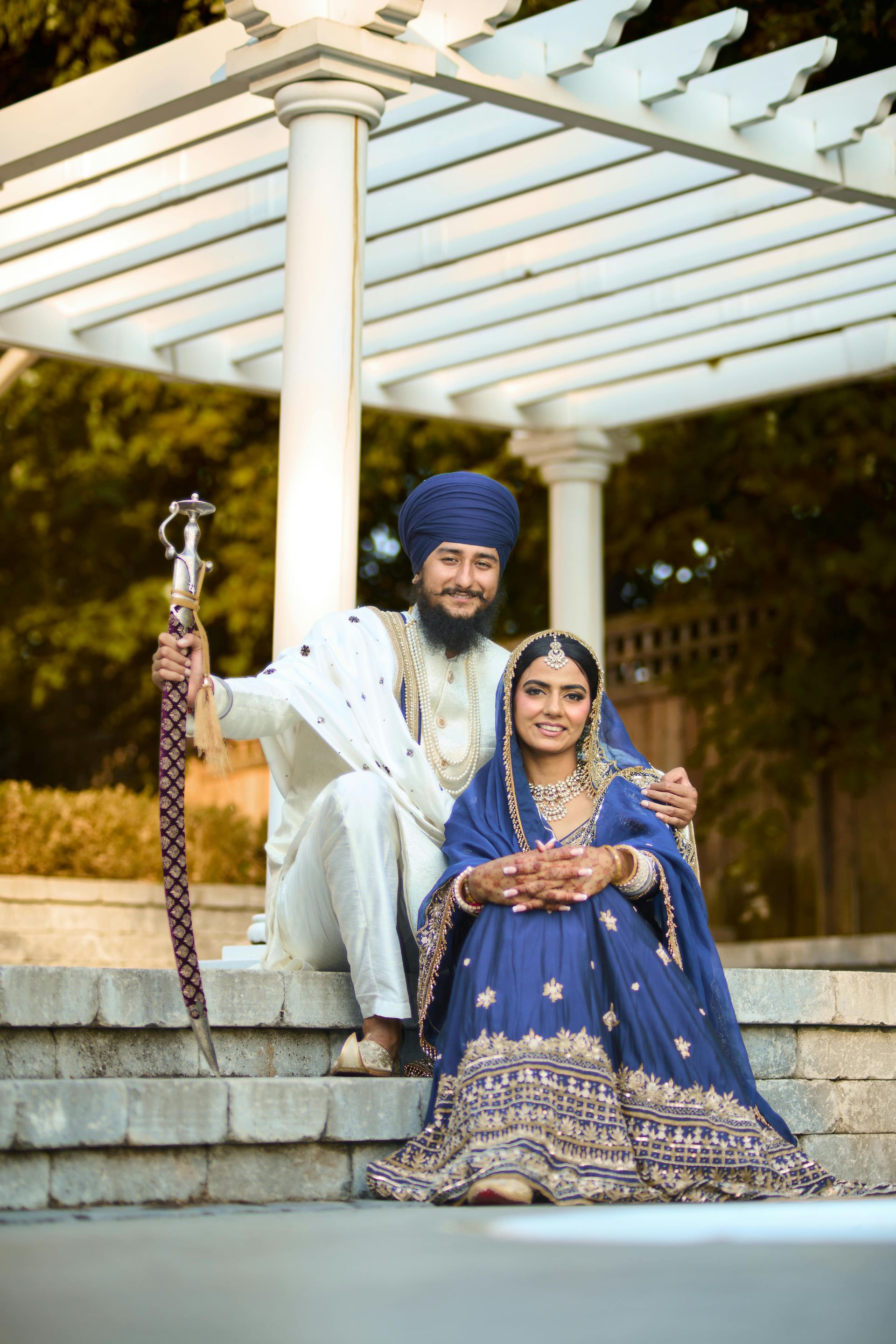 A bride and groom are posing for a picture under a pergola.