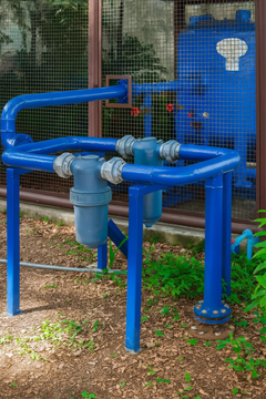 A blue pipe is sitting in the dirt next to a fence.