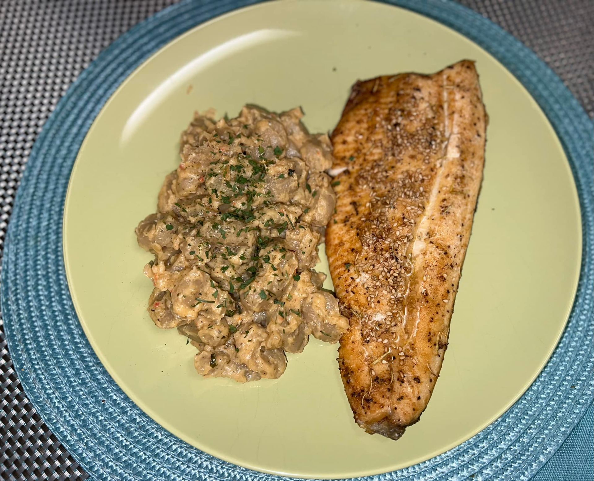 Plated salmon fillet with creamy herb sauce on a pale green plate Plated salmon fillet with creamy herb sauce on a pale green plate