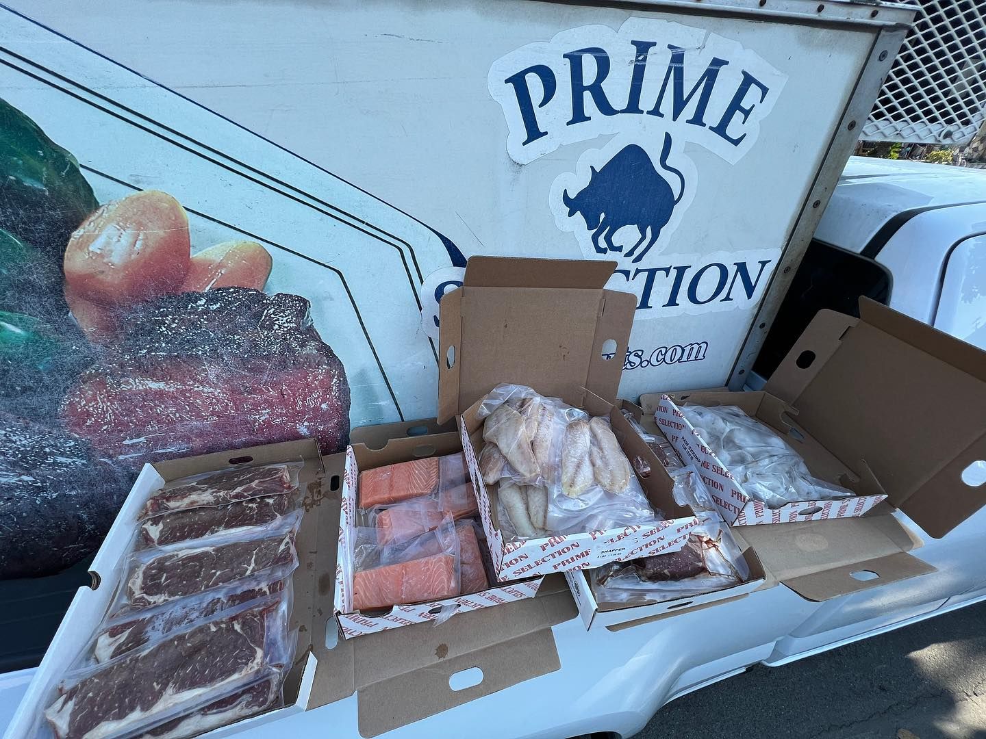 Open seafood display with assorted fish fillets and trays outside a Prime Fish Market sign