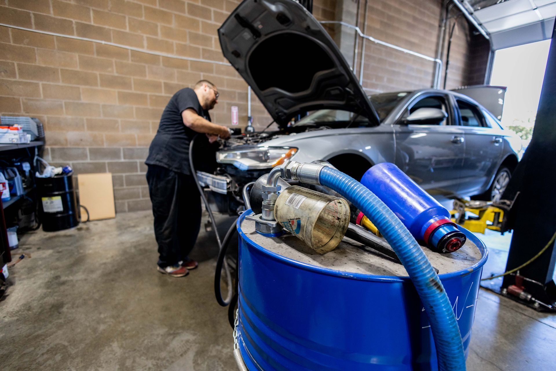 Mechanic working on a car in a garage, with an open hood and tools. | Peak Euro