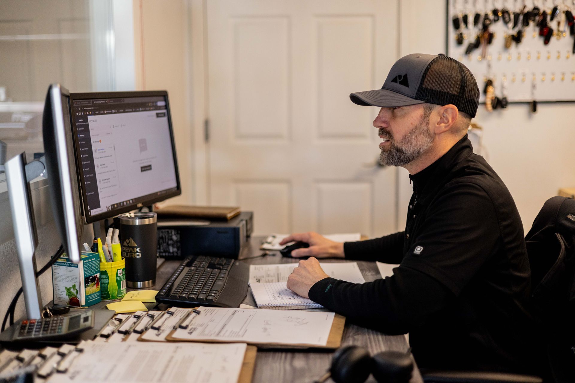 Man in black cap working at a computer in an office, looking at the screen.| Peak Euro
