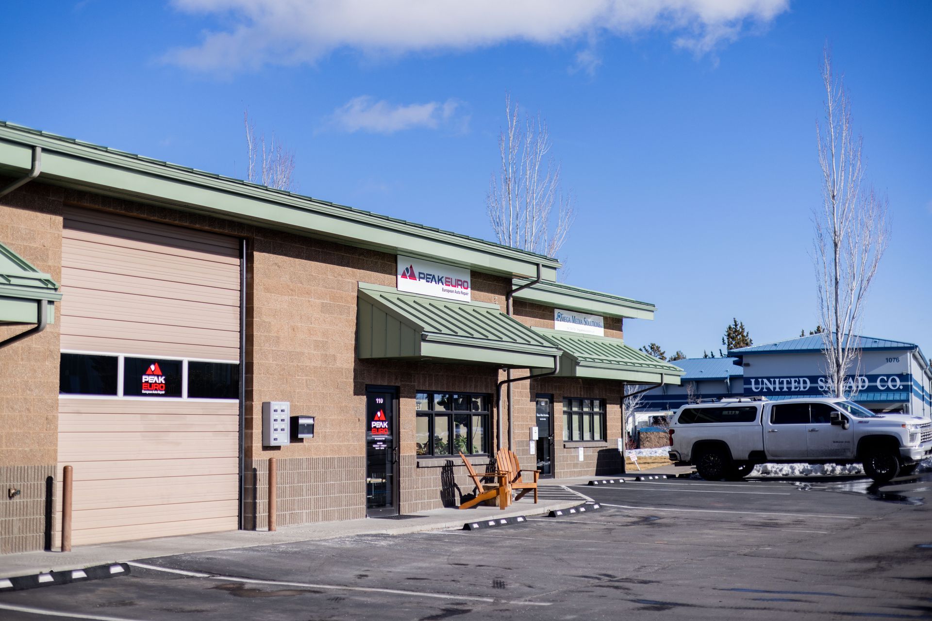 Exterior of a brick commercial building with a garage door, truck parked outside. Blue sky.