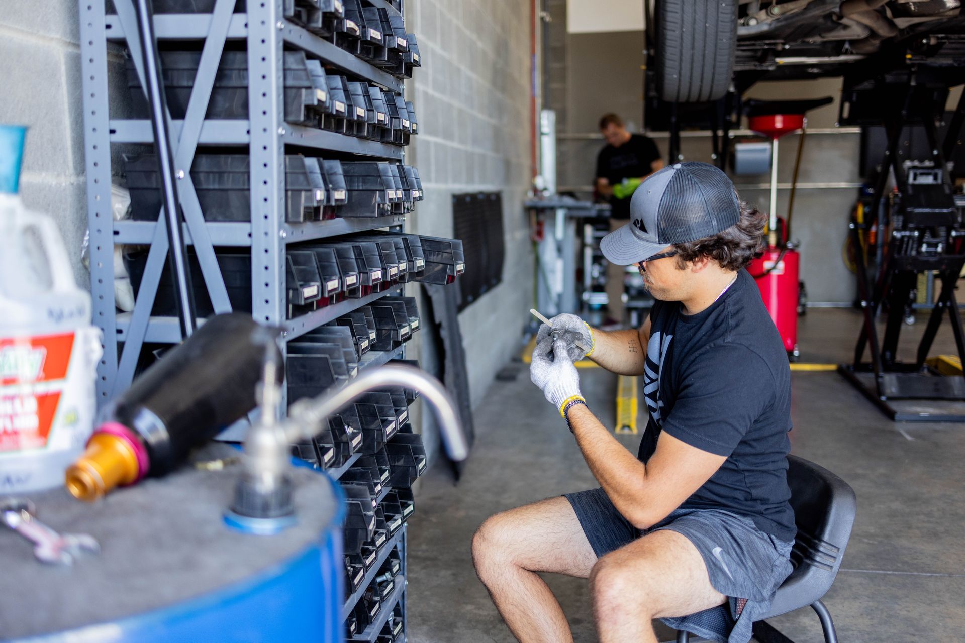 Man in garage working on car parts, surrounded by tools, tires and shelving. | Peak Euro
