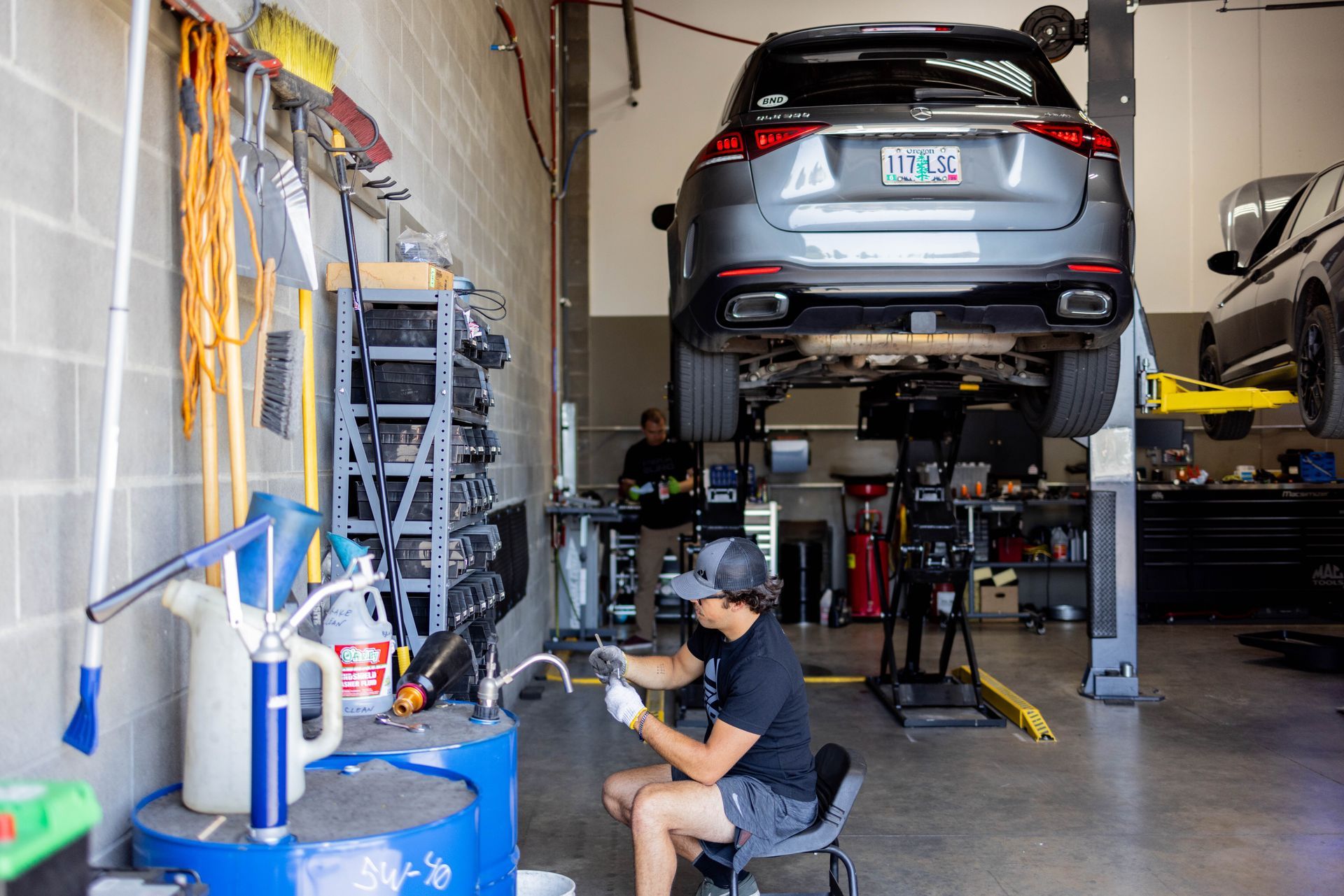 Mechanic working on car raised on a lift in a shop, surrounded by tools and equipment. | Peak Euro