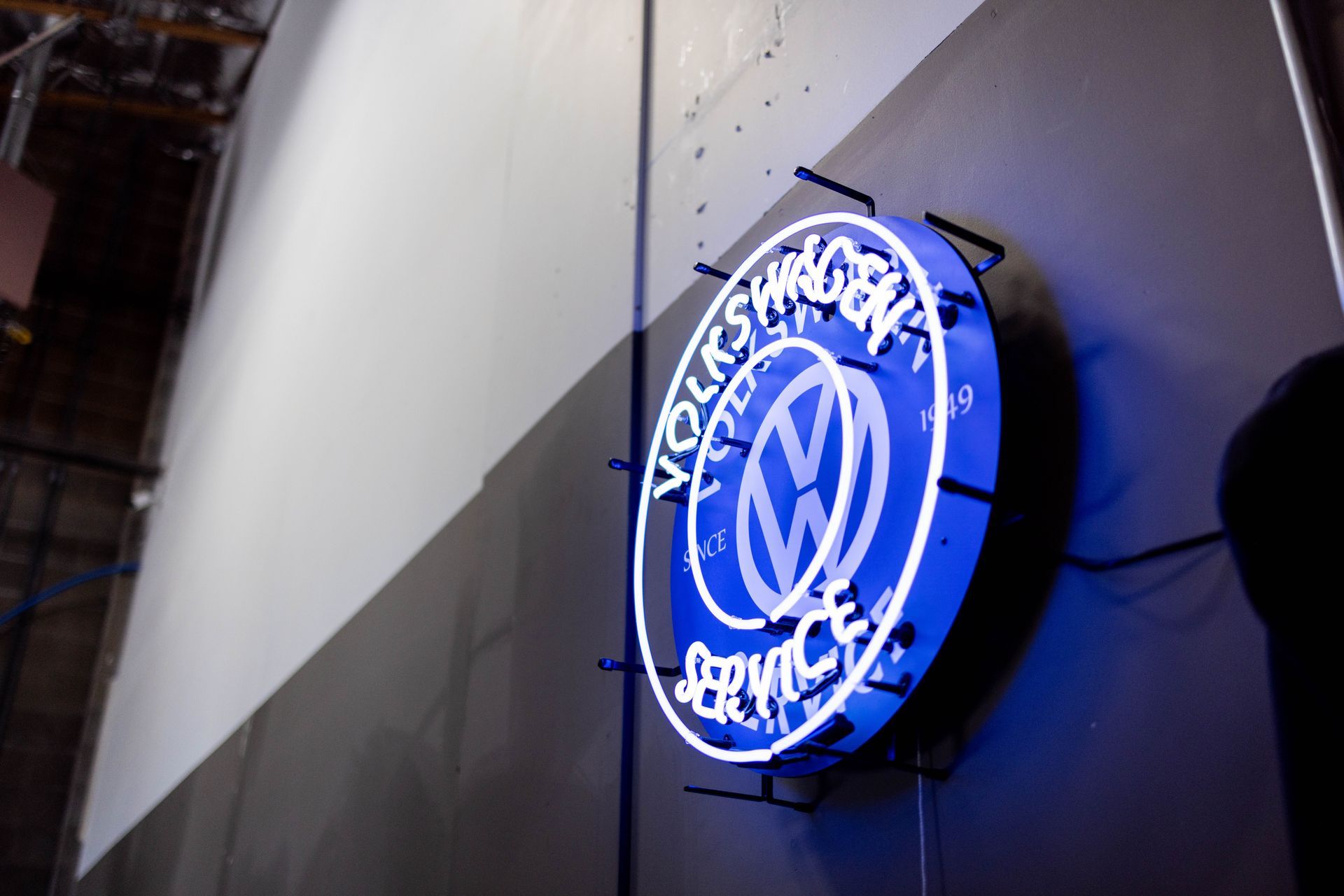 Neon Volkswagen Service sign in blue, mounted on a gray wall. | Peak Euro