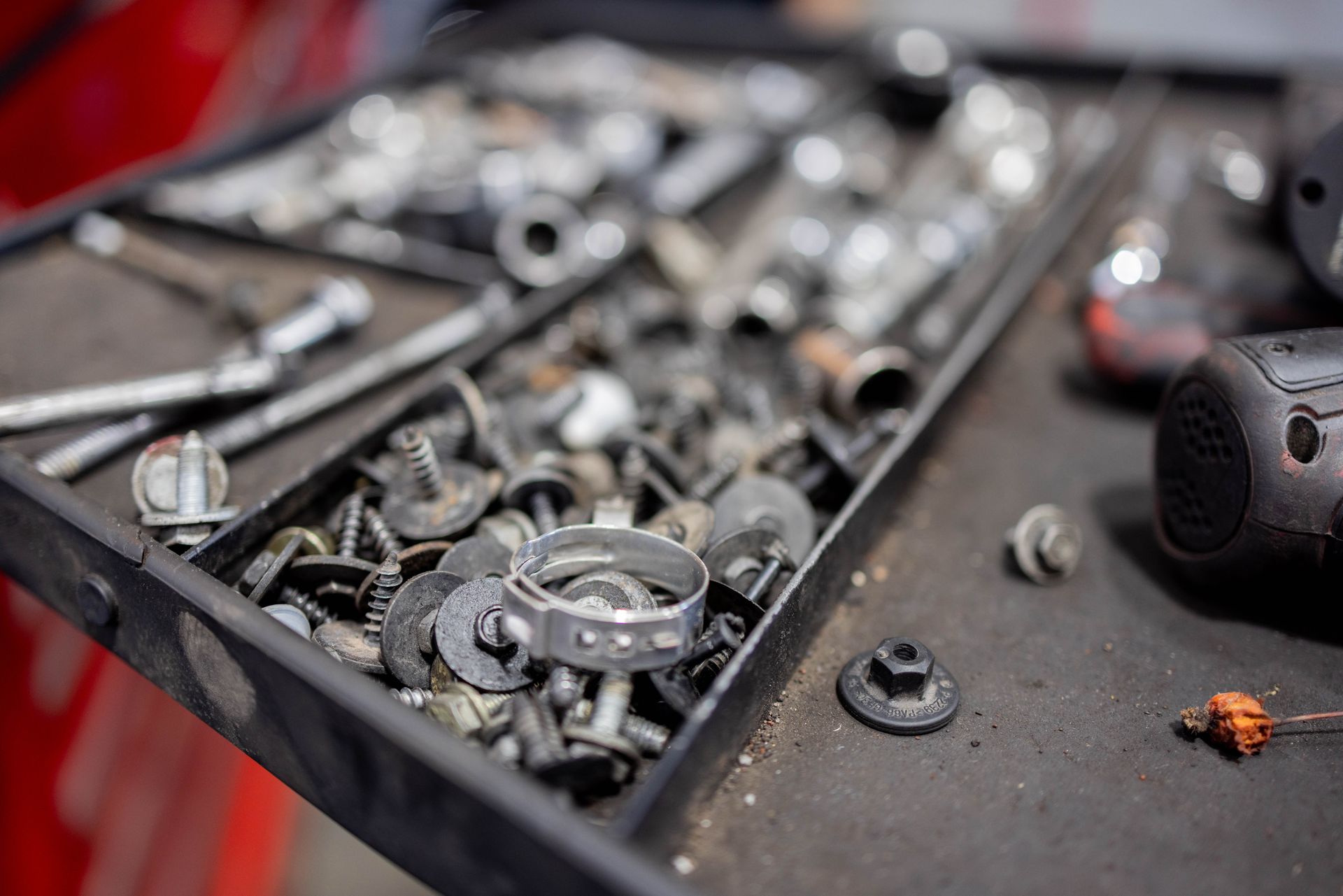 Open drawer filled with various metal screws, bolts, and clamps in a workshop setting. | Peak Euro