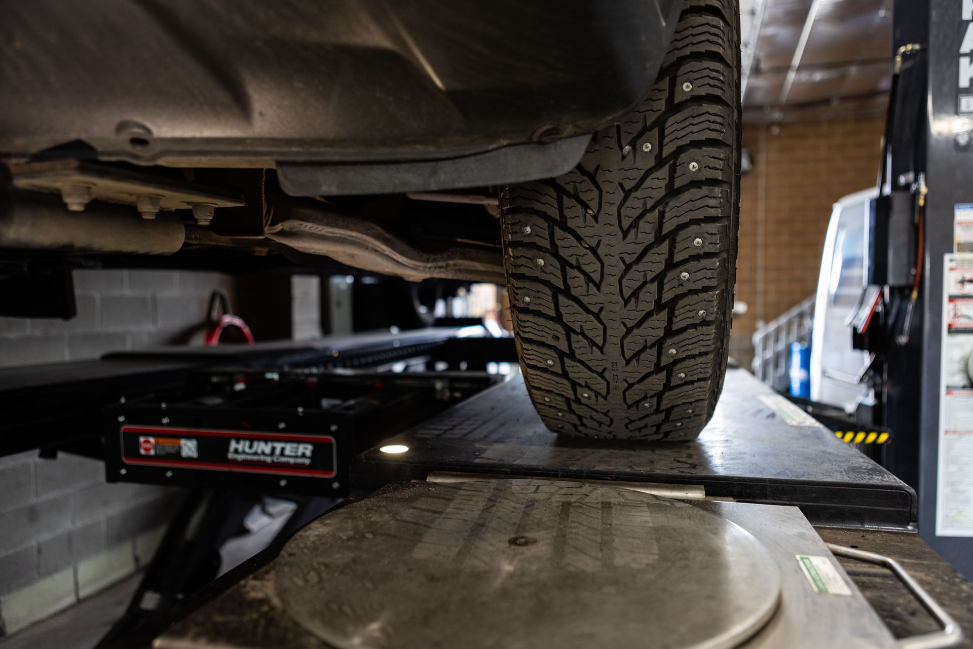 Car tire on a lift, close-up of tread with metal studs; in a repair shop.| Peak Euro