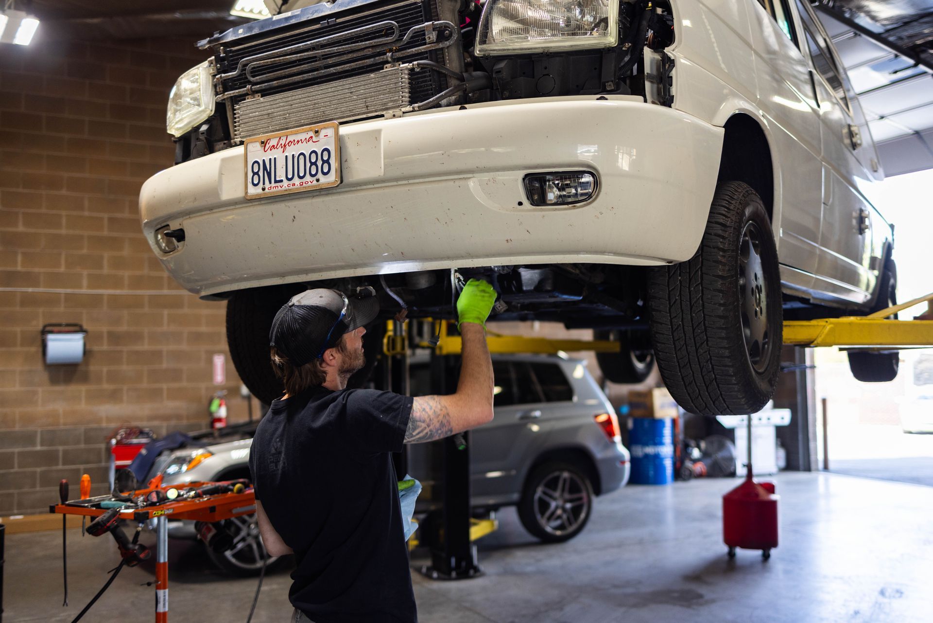 Mechanic works on a white van lifted in a shop. | Peak Euro