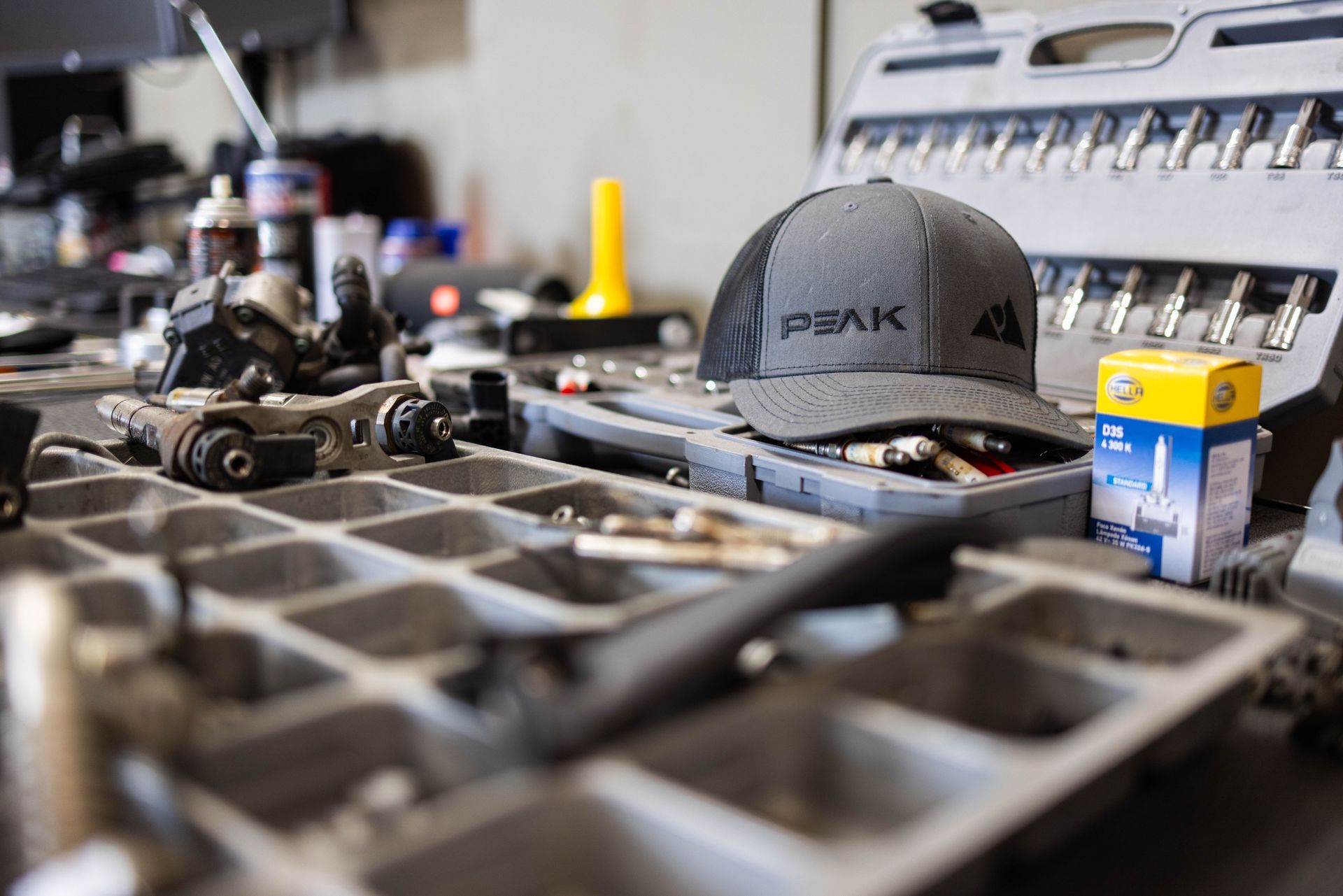 A mechanic's workspace with tools, parts, and a hat. Close-up shot with selective focus. | Peak Euro