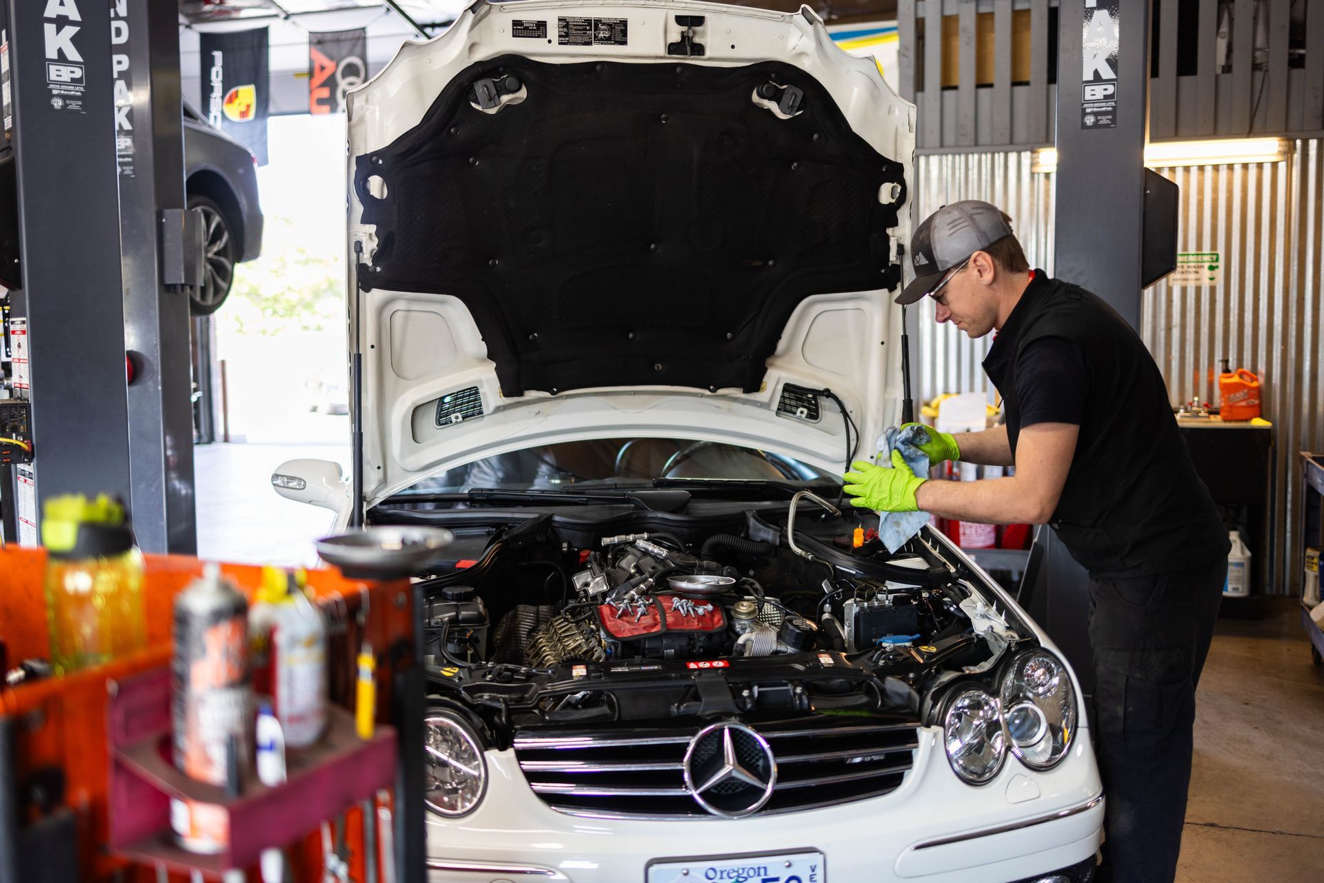 Mechanic cleaning engine of a white Mercedes in a garage. | Peak Euro