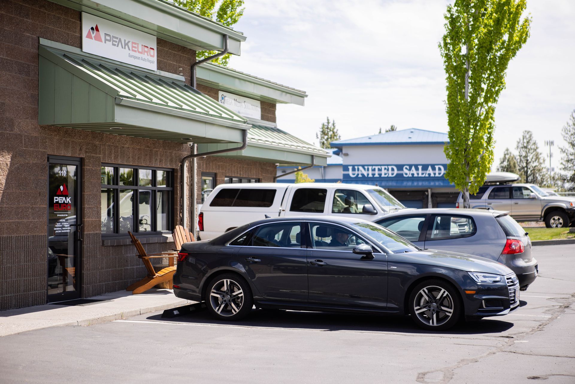 Exterior of a restaurant, gray car parked in front; a white van and other cars in the background. | Peak Euro