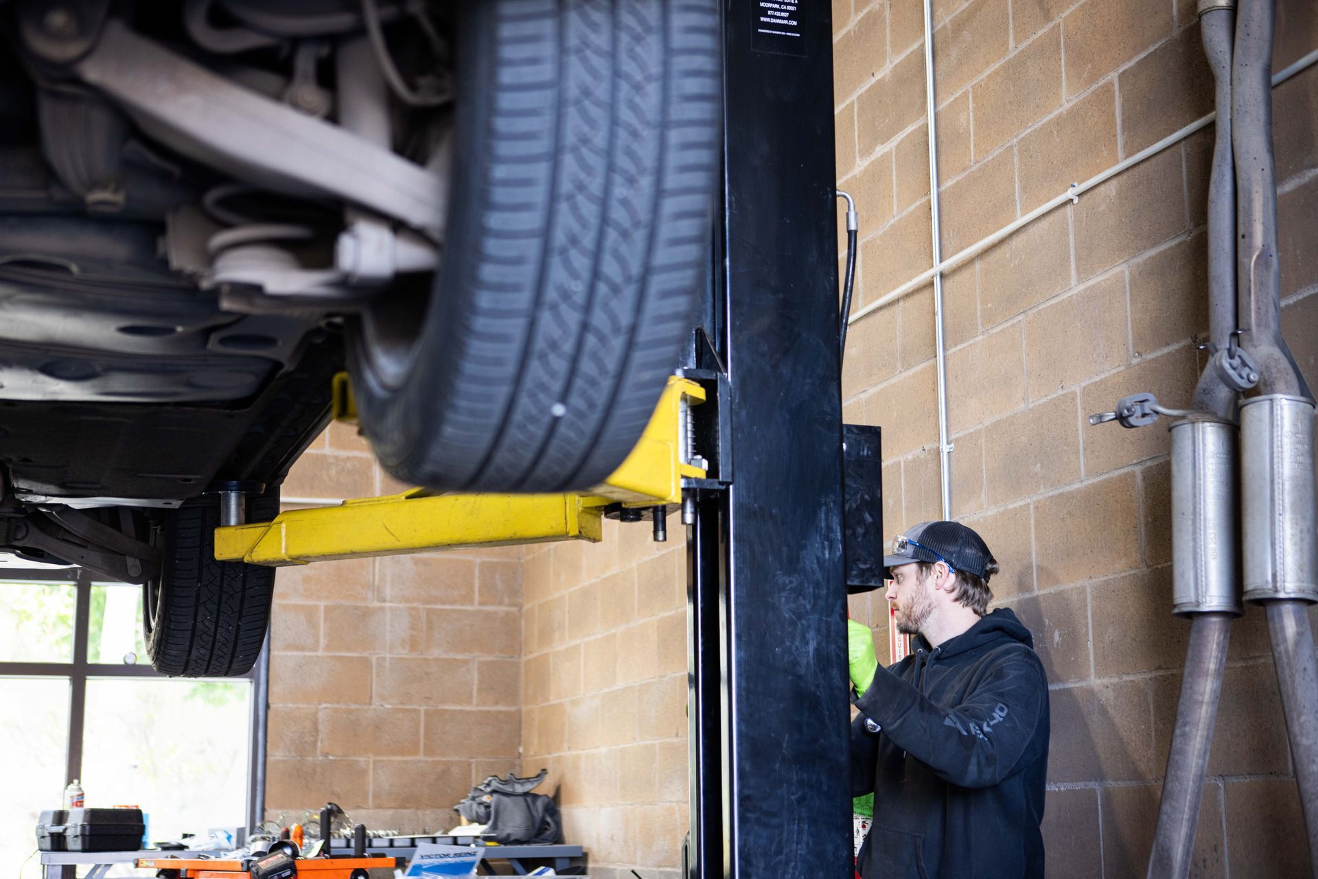 Mechanic inspecting car on a lift in a garage. | Peak Euro