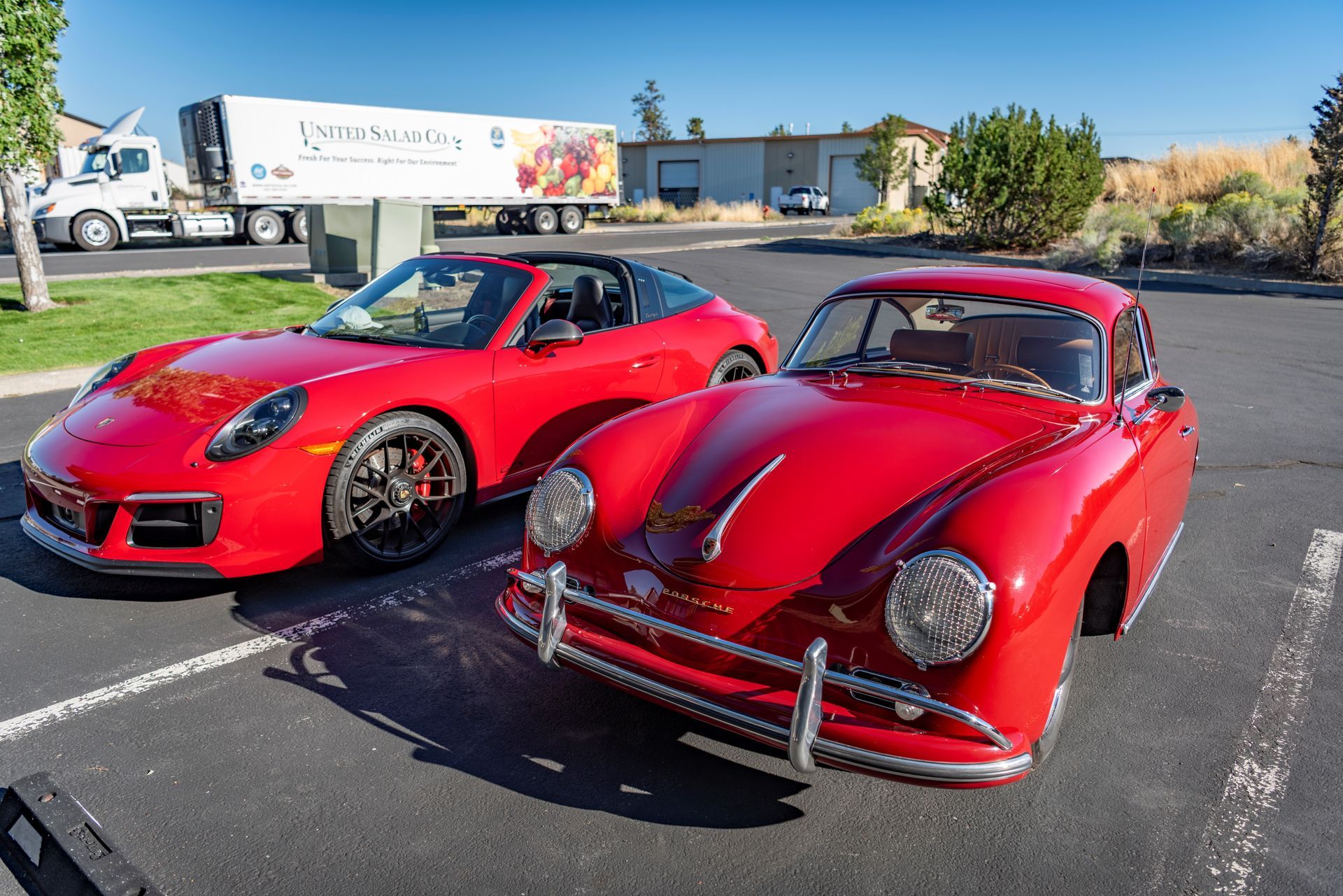 Red classic and modern Porsche cars parked outdoors. A delivery truck is in the background.| Peak Euro