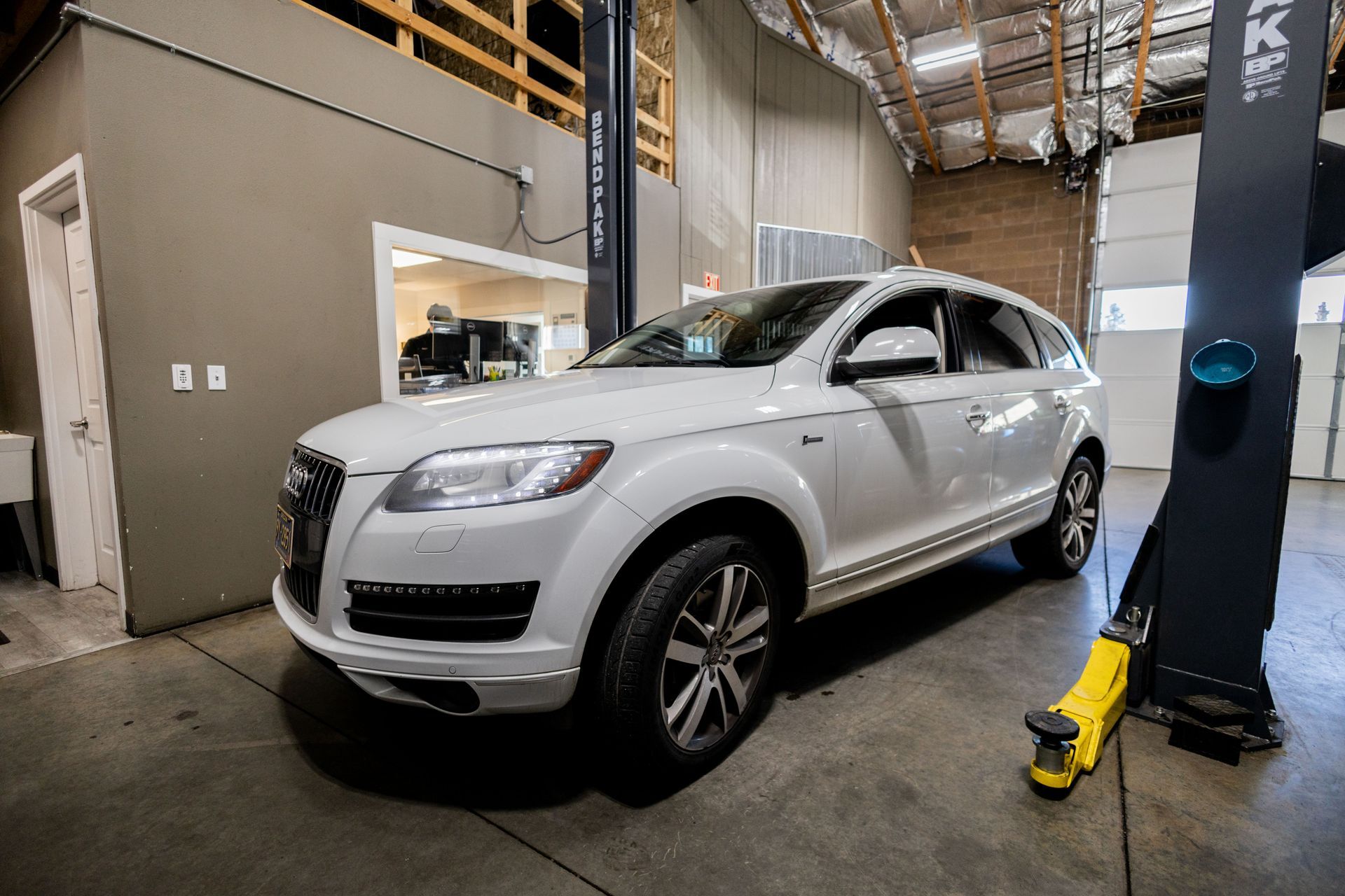 White Audi SUV in an auto repair shop, positioned on a car lift.| Peak Euro