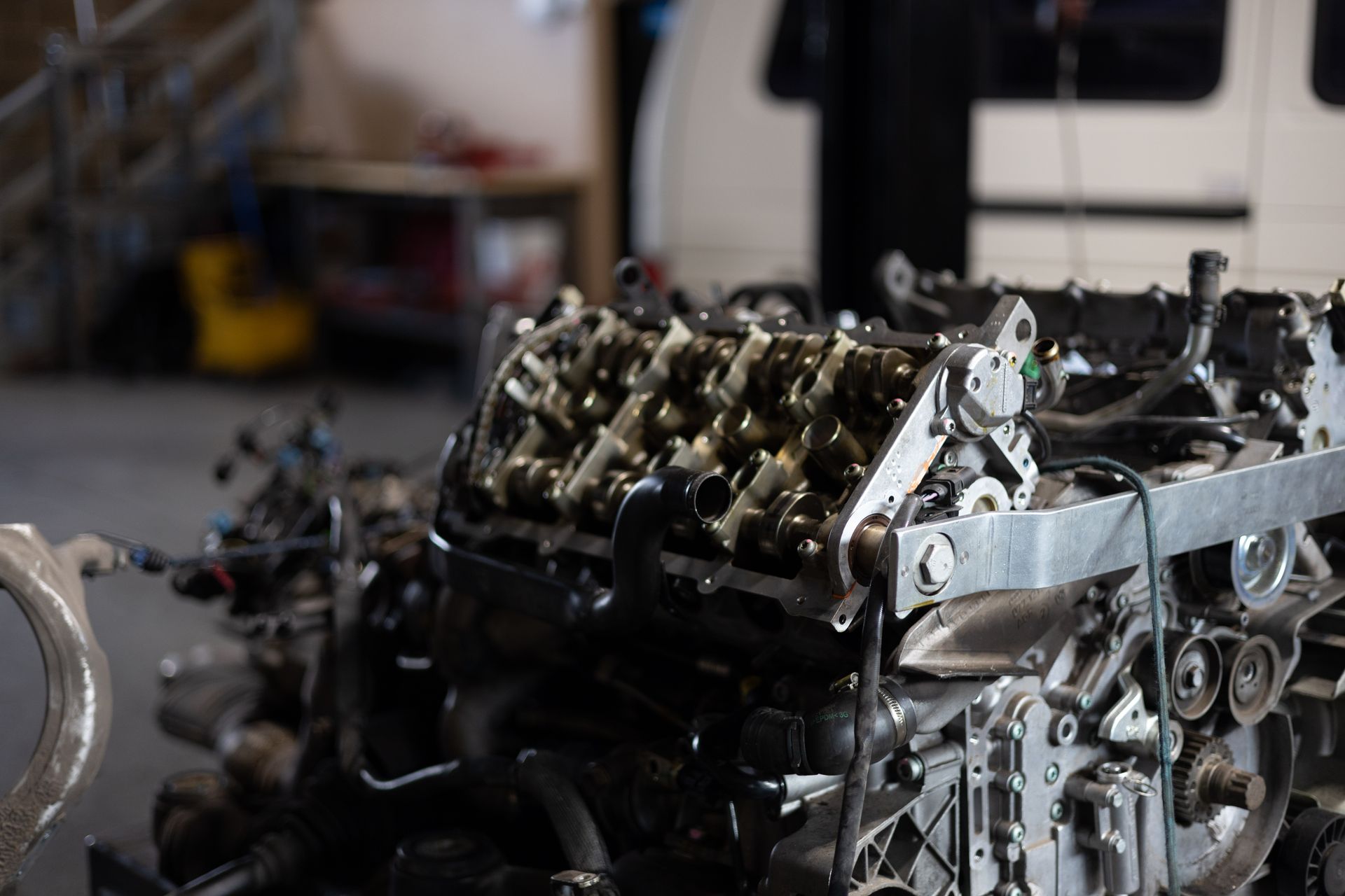 An engine in a garage, the open top showing valves, pulleys, and other parts. | Peak Euro