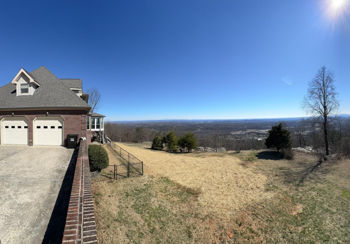 A large house is sitting on top of a hill with a view of a city.