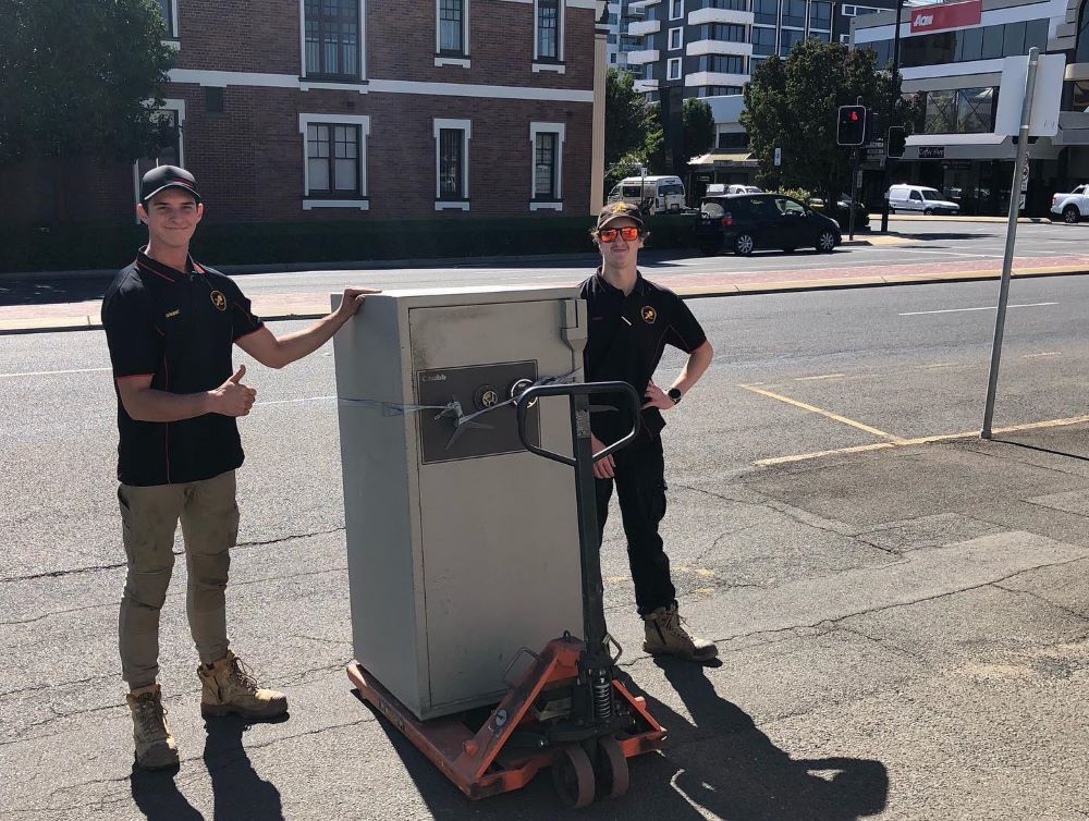 Two Men Are Standing Next to A Safe — Toowoomba Locksmiths in Warwick, QLD