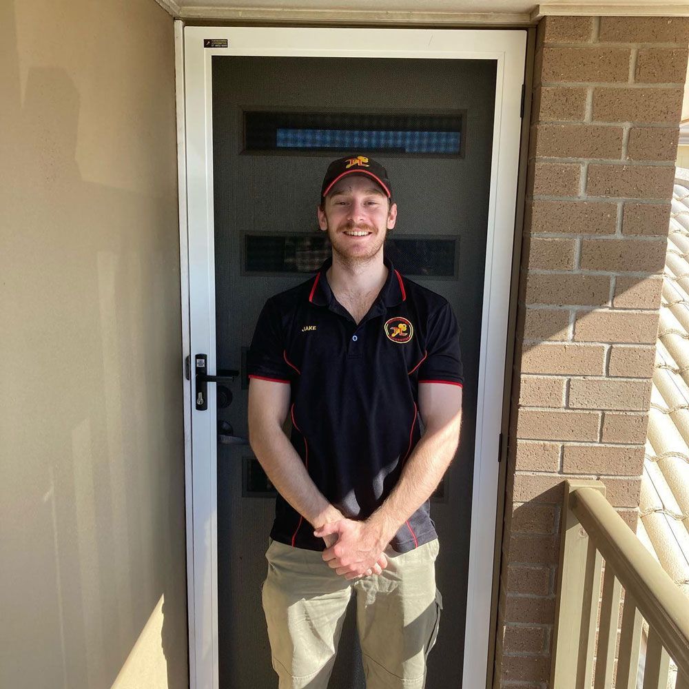 A Man in A Black Shirt Is Standing in Front of A Screen Door — Toowoomba Locksmiths in Toowoomba City, QLD
