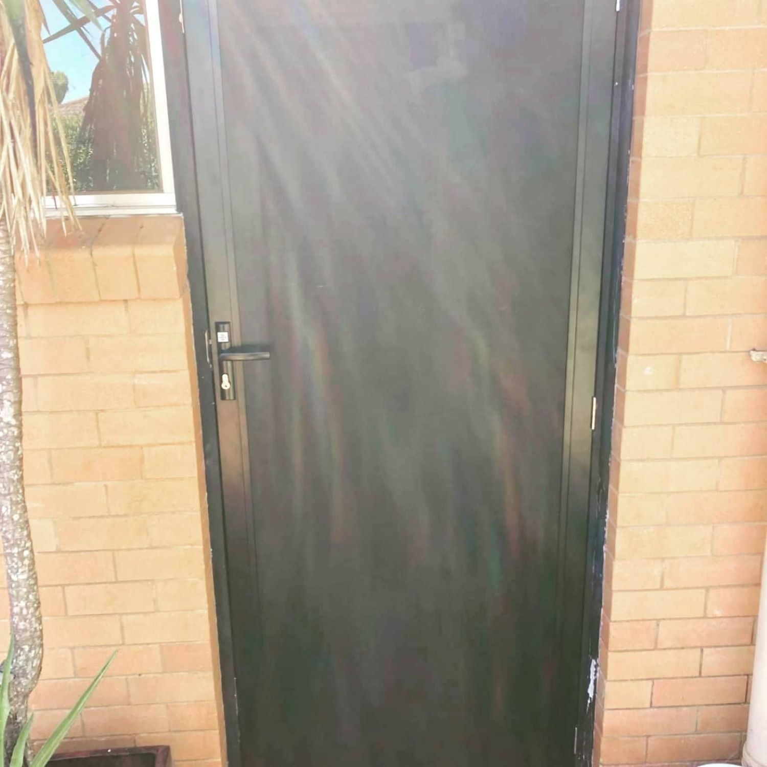 A Black Door Is Sitting on A Brick Wall — Toowoomba Locksmiths in Lockyer Valley, QLD
