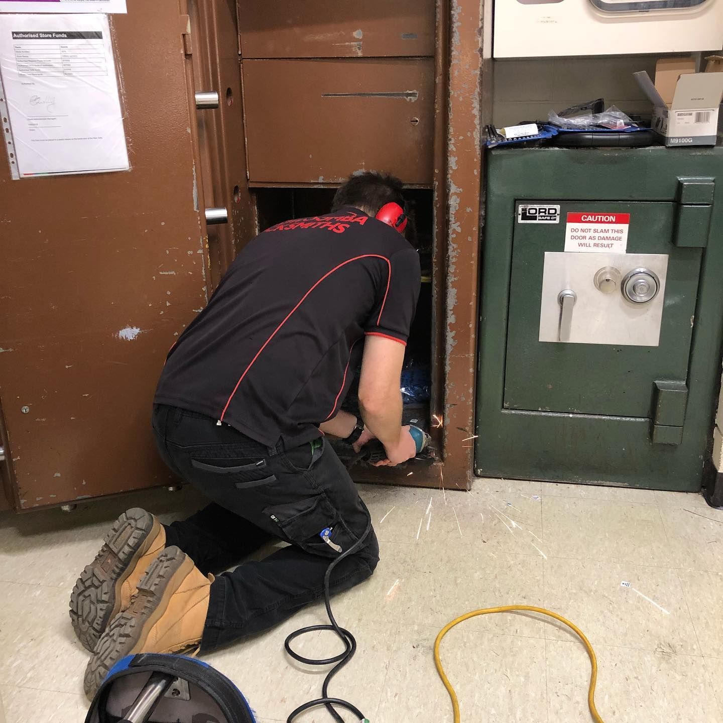 A Man Is Kneeling Down in Front of A Safe — Toowoomba Locksmiths in Gatton, QLD