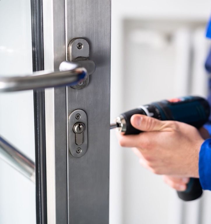 A Person Is Fixing a Door with A Drill — Toowoomba Locksmiths in Toowoomba City, QLD