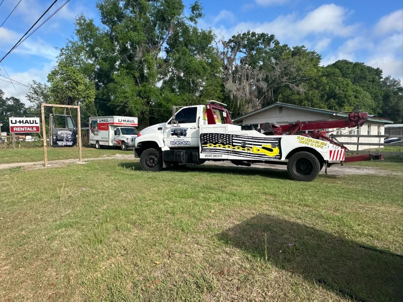 Tow truck parked on grass next to a U-Haul facility.