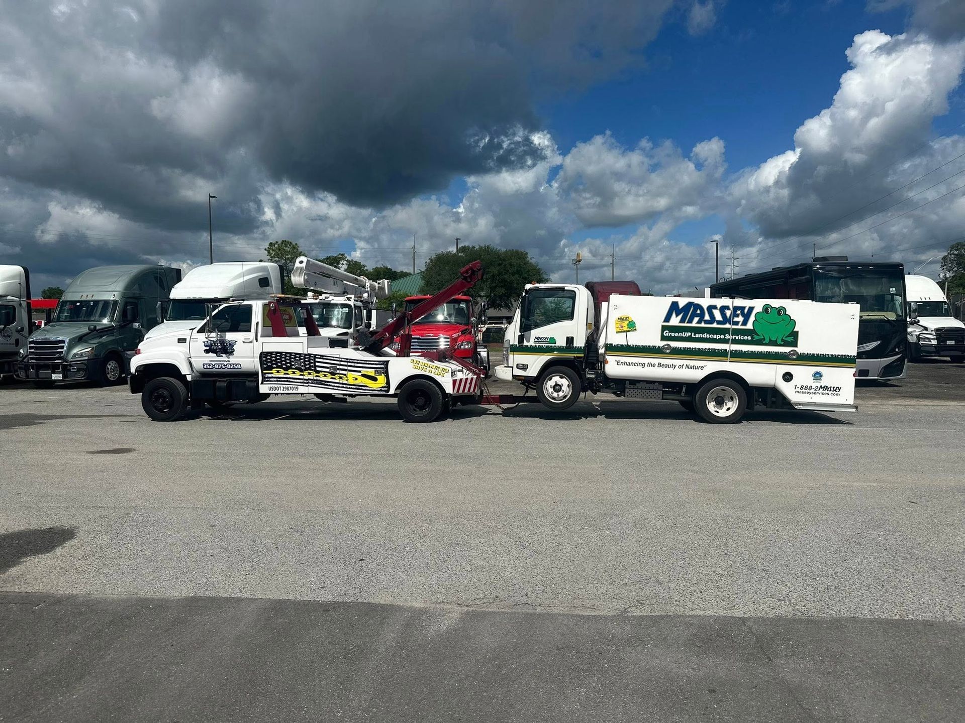 White truck towing a service vehicle, both with Massey branding, parked in a lot.