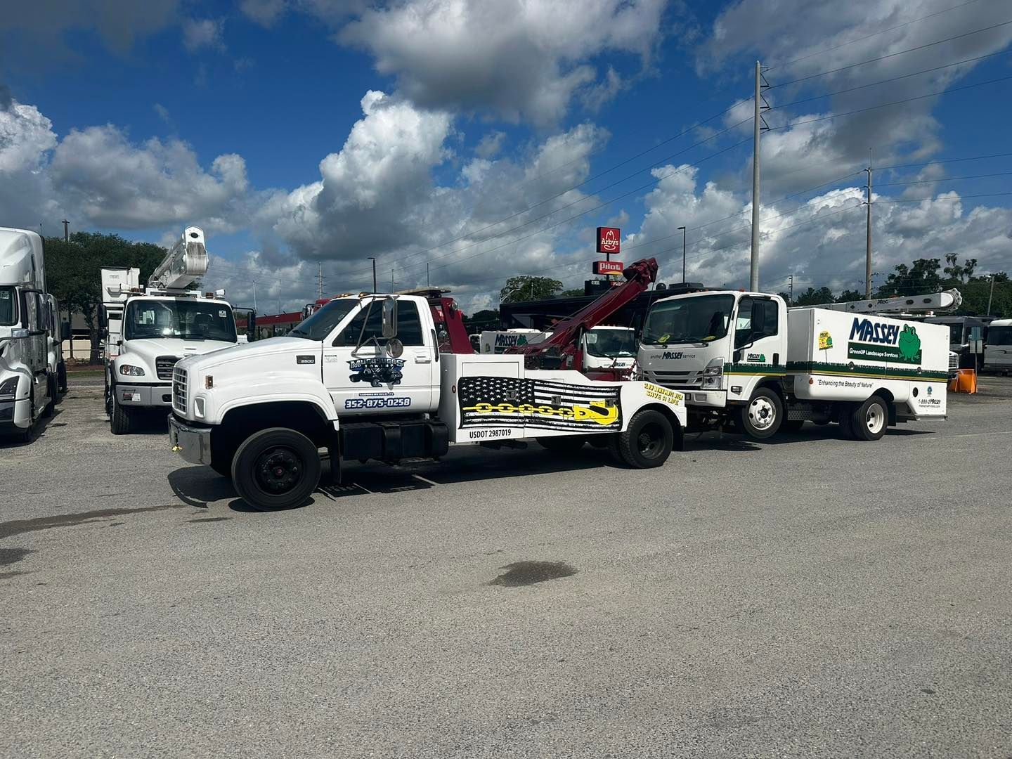 Tow trucks parked on a sunny day in a parking lot. White trucks, blue sky.