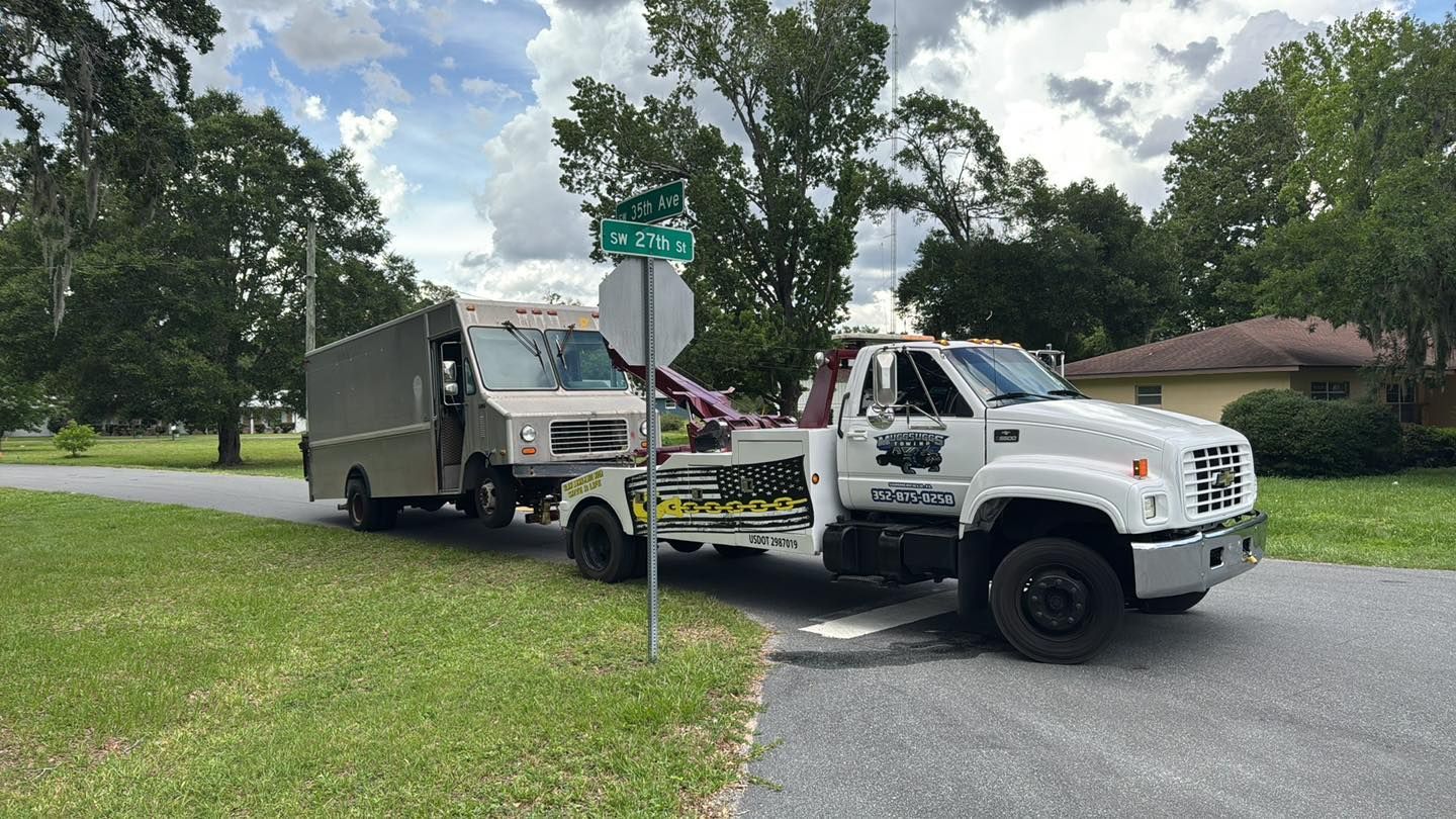 A tow truck pulling a box truck on a residential street.
