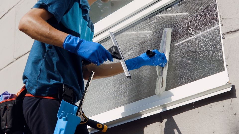 A man is cleaning a window with a squeegee.