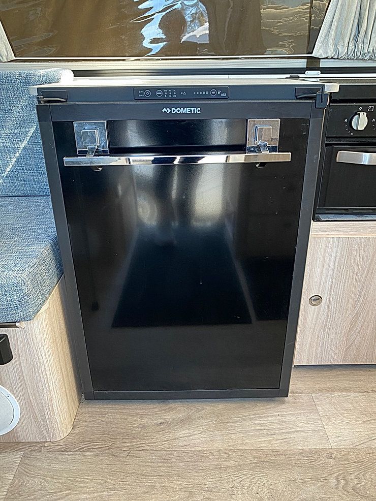A Black Refrigerator Is Sitting In A Kitchen Next To A Stove — Great Lakes Caravans In Nabiac, NSW