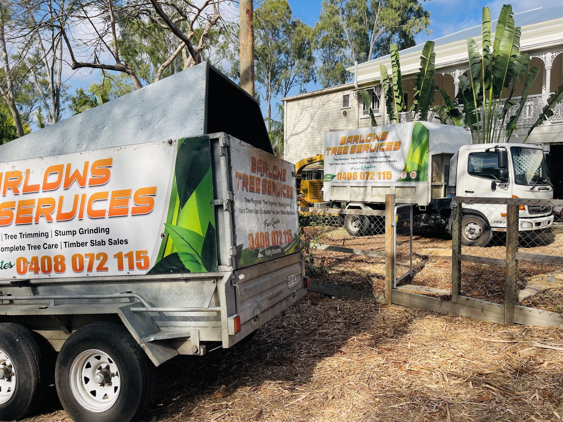 People in Orange Shirts Working on a Tree in a Sunny Backyard — Barlows Tree Services in Rockhampton, QLD