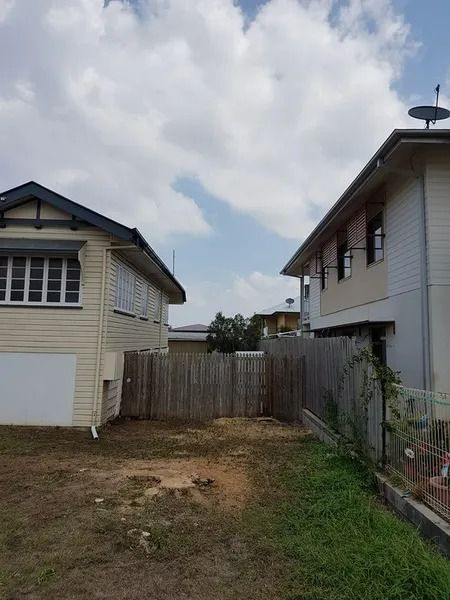 Narrow Grassy Yard Between Two Houses With a Wooden Fence — Barlows Tree Services in Rockhampton, QLD
