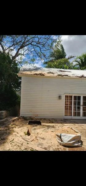 Small House With a Damaged Roof in a Sandy Yard, With Trees — Barlows Tree Services in Rockhampton, QLD