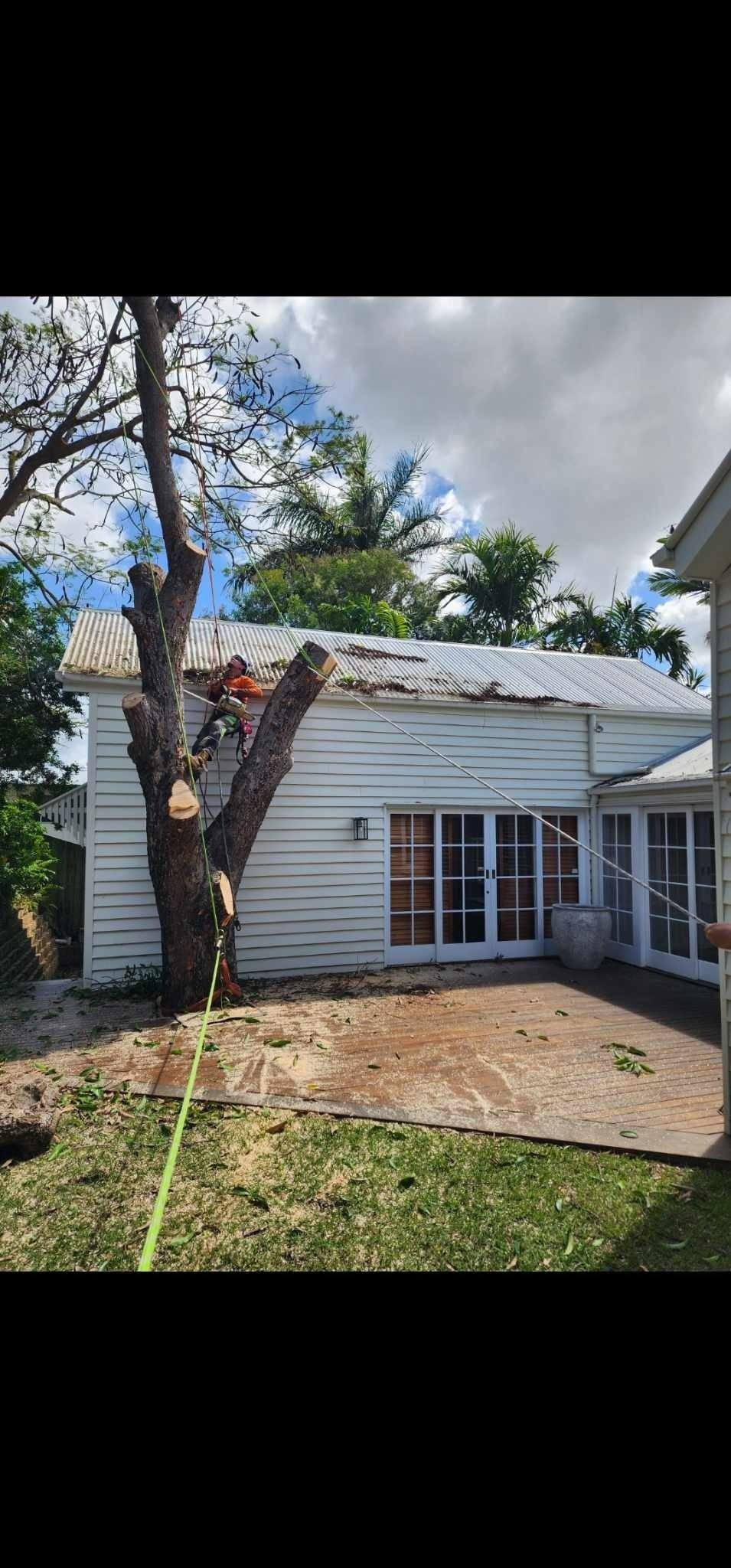 Small White House With a Porch, Tree in Front, and a Partly Cloudy Sky — Barlows Tree Services in Rockhampton, QLD