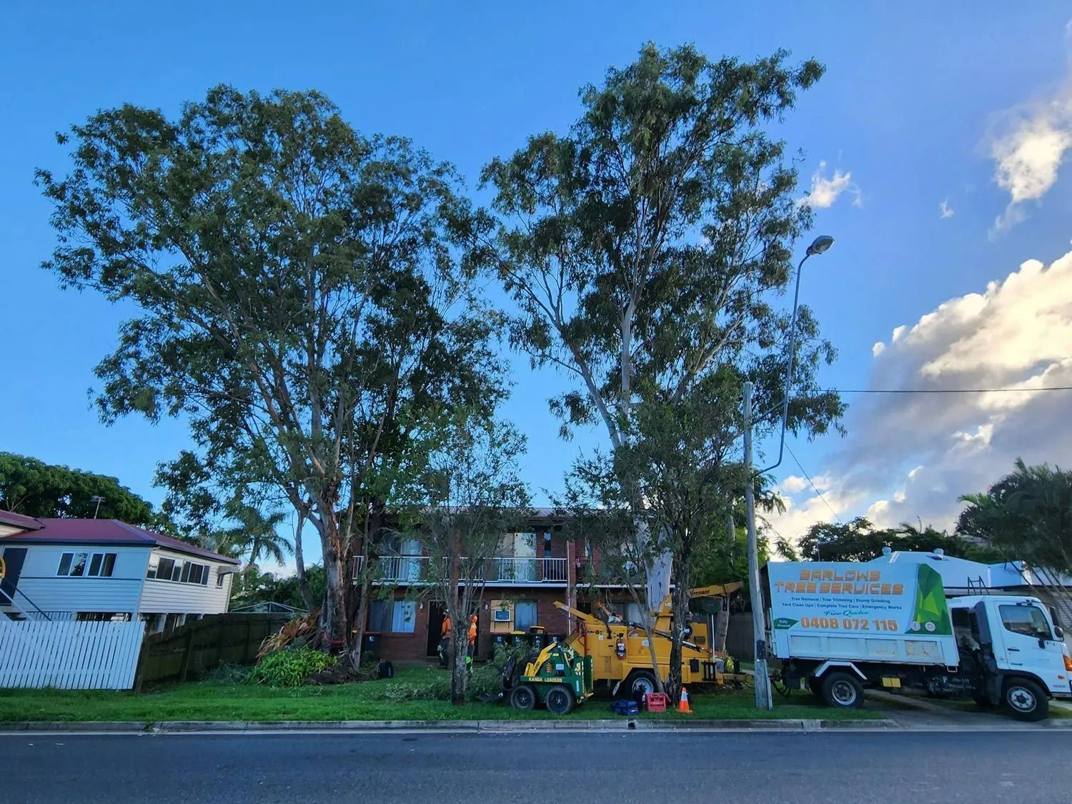 Trees Being Trimmed Next to a House With a Chipper — Barlows Tree Services in Rockhampton, QLD