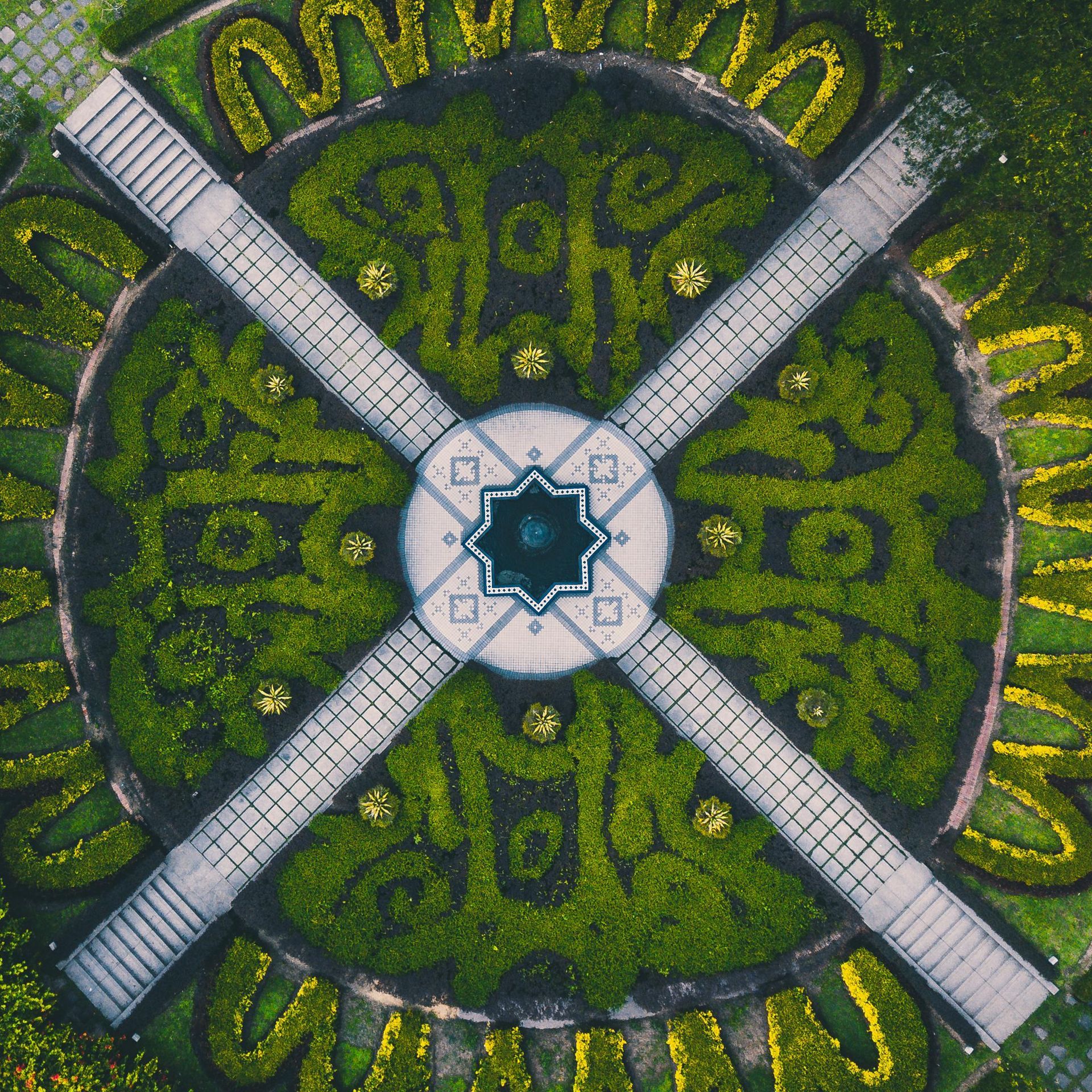 An aerial view of a circular garden with a fountain in the middle