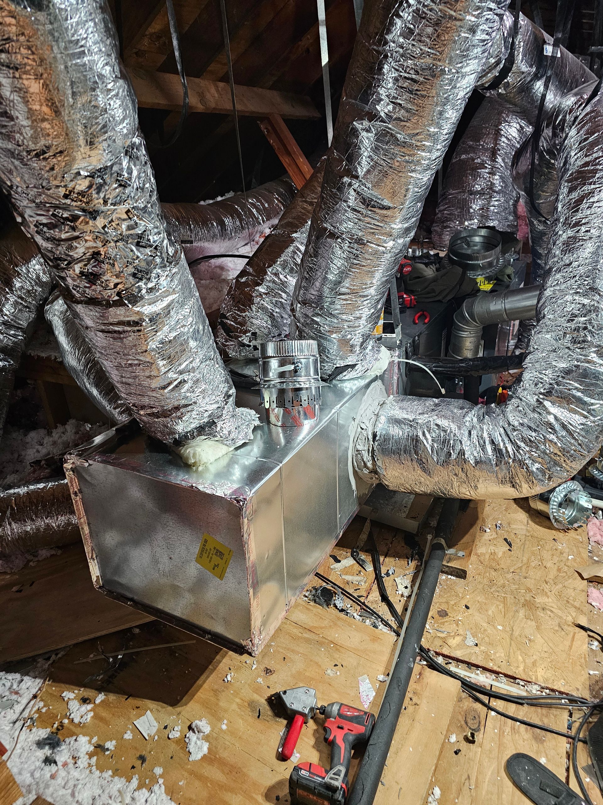 A bunch of aluminum ducts are sitting on top of a wooden floor.