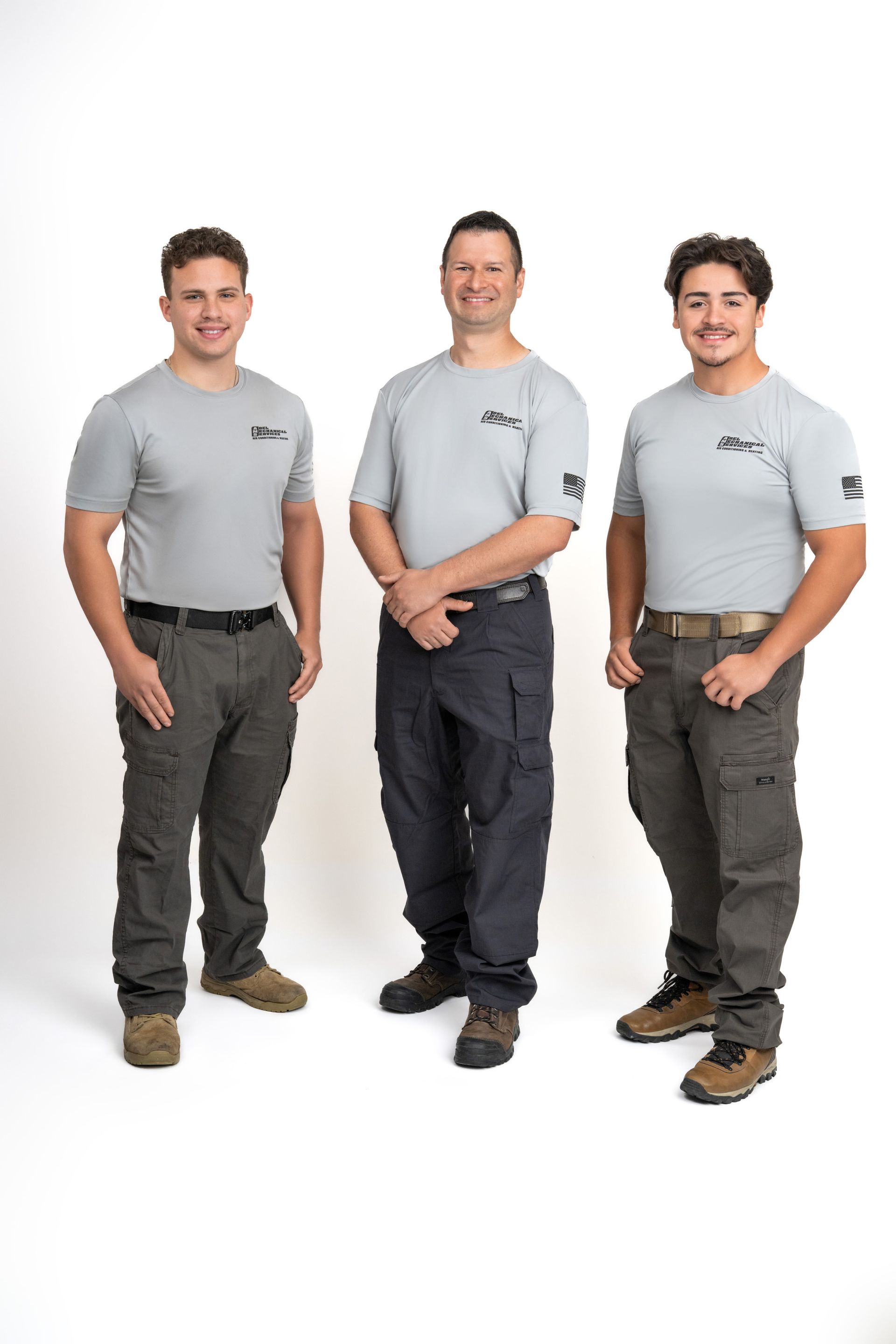 Three men are standing next to each other on a white background.