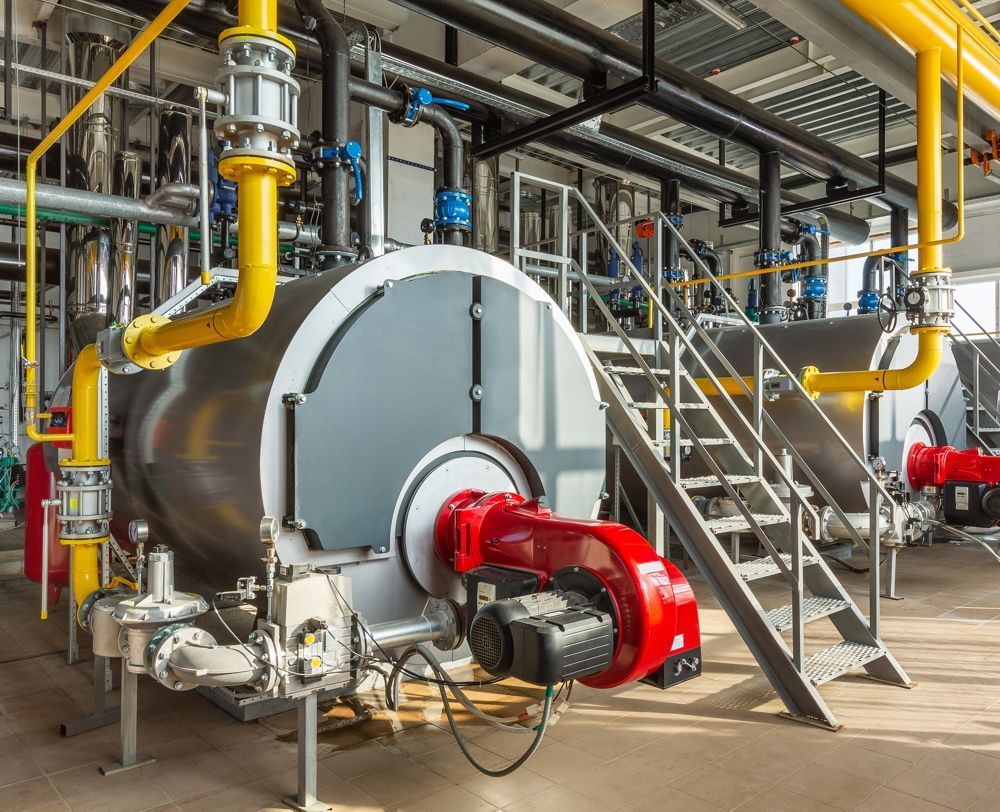 Industrial boiler with yellow pipes and a red burner.