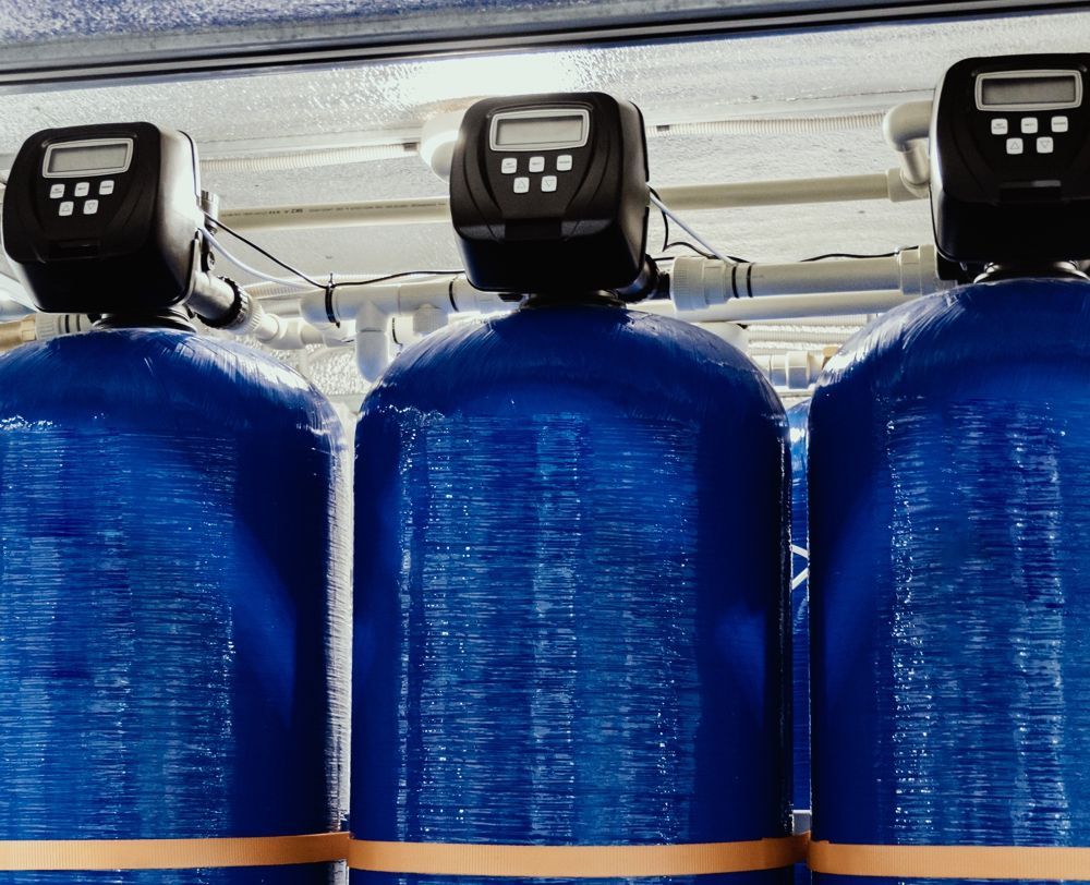 Three blue water filtration tanks with digital control panels.