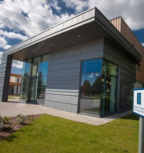 Modern building with gray facade, glass windows, and a grassy lawn.